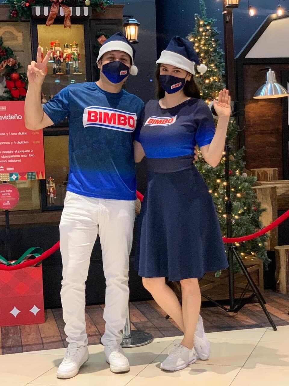 Anfitriones con gorros navideños en una activación de temporada en un centro comercial
