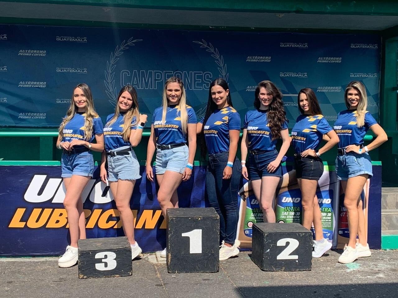 Equipo de edecanes de AURA celebrando en el podio de una carrera en el autódromo en Guatemala